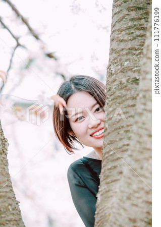 A woman peeking through a tree 111776199