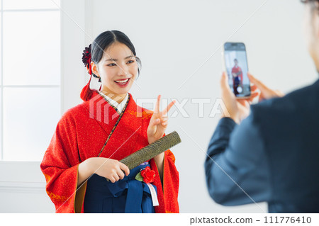 一名男子正在為一名穿著袴的女子拍照 111776410