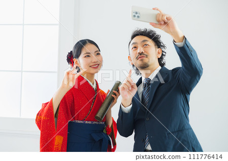 一名男子正在為一名穿著袴的女子拍照 111776414