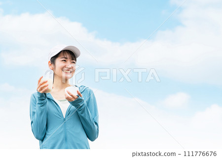 Asian woman in sportswear training while drinking protein in the park for body shaping Asian woman in sportswear training while drinking protein in the park for body shaping 111776676