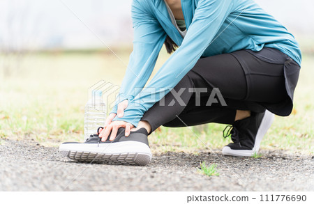 Asian woman in sportswear hurting and touching her ankle while exercising 111776690