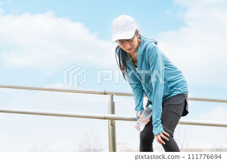 An Asian woman whose knees hurt during exercise due to overwork. 111776694
