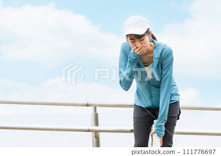 Asian woman in sportswear who is troubled by nausea and dizziness during exercise 111776697