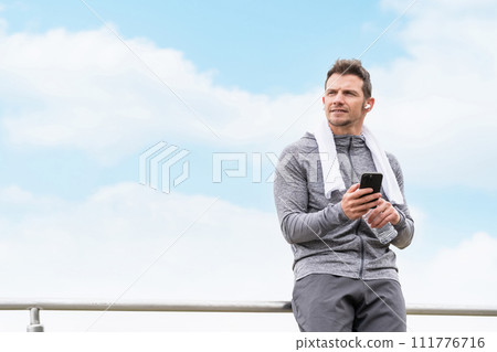 穿著運動服的白人男子在鍛煉/訓練時用智能手機上的耳機聽音樂 穿著運動服的白人男子在鍛煉/訓練時用智能手機上的耳機聽音樂 111776716