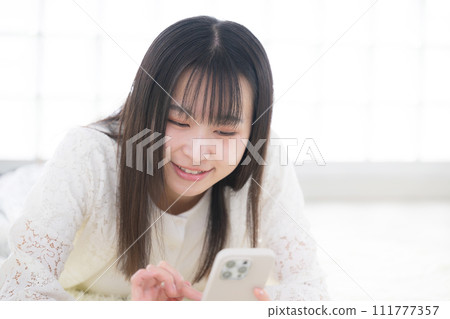 一位女士躺著操作智慧型手機 111777357