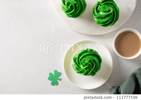 Patrick's Day homemade cupcake with green whipped cream with shamrock on white background. View from above. Copy space. Patrick's Day homemade cupcake with green whipped cream with shamrock on white background. View from above. Copy space. 111777506