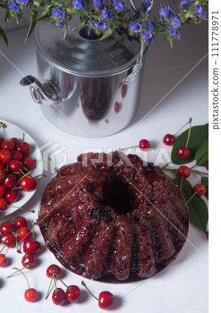 Chocolate cake with sweet cherry, vintage kettle and bouquet of blue flowers on white background.. 111778971