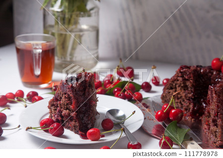 Chocolate cake with sweet cherry, cup of tea and bouquet of blue flowers on white background.. 111778978