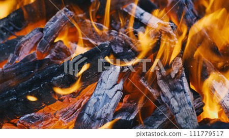 Close-up of burning wood in a fire. Red and yellow flames of the fire. Wood burning in a brazier for cooking on coals. 111779517