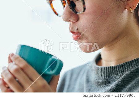 Young woman holding a cup with both hands to cool a drink 111779903