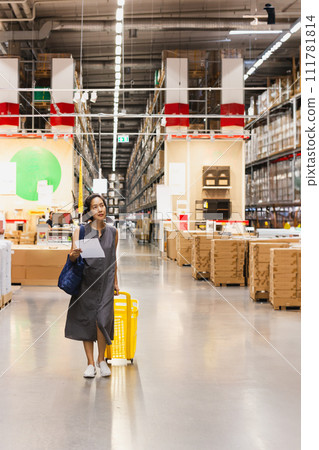 Woman with cart looking for houshold goods on a warehouse. Woman with cart looking for houshold goods on a warehouse. 111781814
