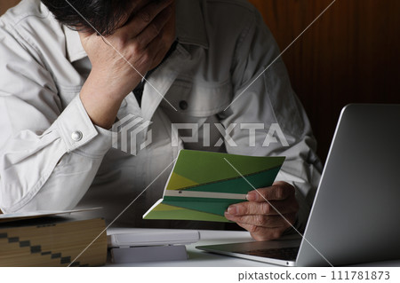 A man in work clothes worries with his passbook in hand 111781873