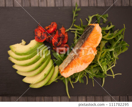 Baked sea trout fillet with fresh vegetables and herbs on black board 111782295