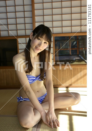 一位穿著比基尼泳衣的年輕女子坐在古民宅的日式房間裡 111783181