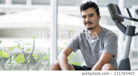 A young male athlete takes a break after exercising in a gym 111783407