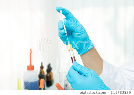 Researcher or scientists loads liquid into blood sample in test tube. Researchers are developing vaccines and medicine to treat the COVID-19 virus. 111783529