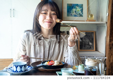 Woman eating pancake 111784104