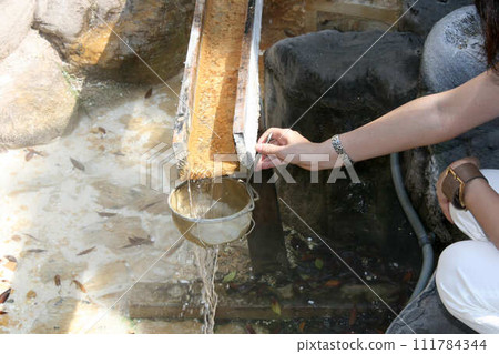 A woman washes coins in hot water Benzaiten at Atagawa Onsen A woman washes coins in hot water Benzaiten at Atagawa Onsen 111784344