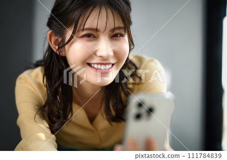 Housewife operating a smartphone in the room 111784839