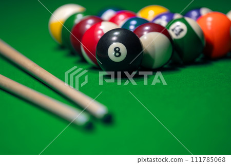 Many colorful billiard balls and cue on green table 111785068