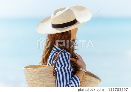 relaxed elegant female on seacoast with straw bag 111785397
