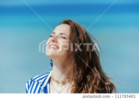happy elegant woman on ocean shore enjoying tranquility 111785401