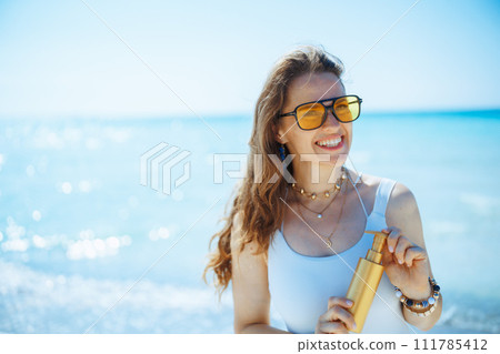 happy stylish 40 years old woman on ocean coast with spf 111785412