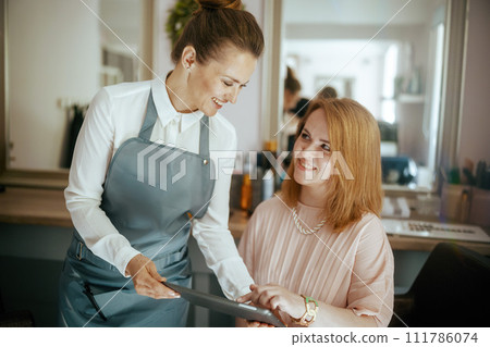 woman hair salon worker in modern hair studio with tablet PC woman hair salon worker in modern hair studio with tablet PC 111786074