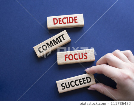 Decide Commit Focus Succeed symbol. Concept words Decide Commit Focus Succeed on wooden blocks. Businessman hand. Beautiful deep blue background. Business concept. Copy space. 111786483