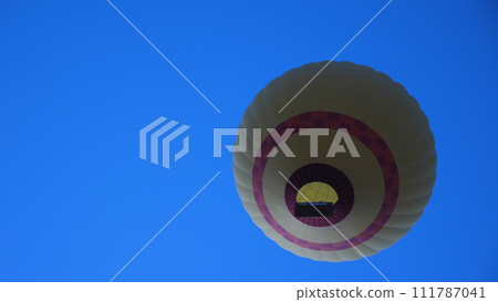 Bottom view of balloon flight with bright flame against blue sky. Unusual angle. Ballooning in Cappadocia. Close-up view. Bottom view of balloon flight with bright flame against blue sky. Unusual angle. Ballooning in Cappadocia. Close-up view. 111787041