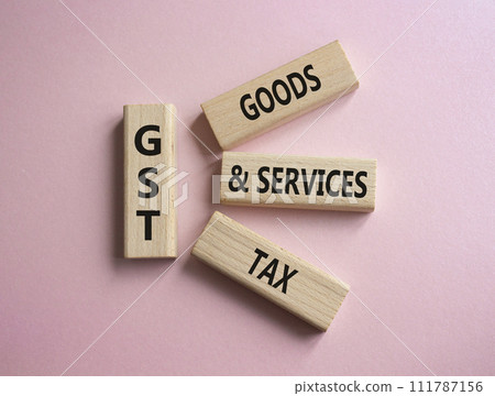 GST - Goods and Services Tax symbol. Concept word GST on wooden blocks. Beautiful pink background. Business and GST concept. Copy space. GST - Goods and Services Tax symbol. Concept word GST on wooden blocks. Beautiful pink background. Business and GST concept. Copy space. 111787156