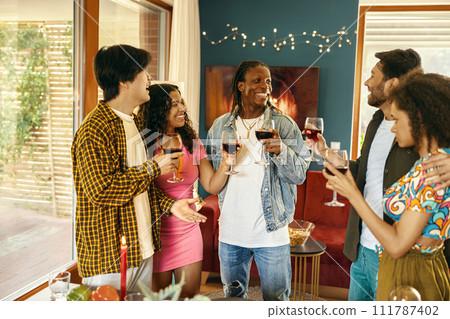 Happy young friends drinking red wine and enjoying time together at holiday party at home Happy young friends drinking red wine and enjoying time together at holiday party at home 111787402