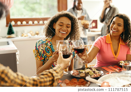 Close up of happy friends is drinking wine and clinking glasses having holiday dinner party at home 111787515