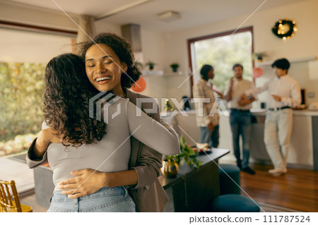 Smiling friends hugging and enjoy time spent together on holiday home party Smiling friends hugging and enjoy time spent together on holiday home party 111787524
