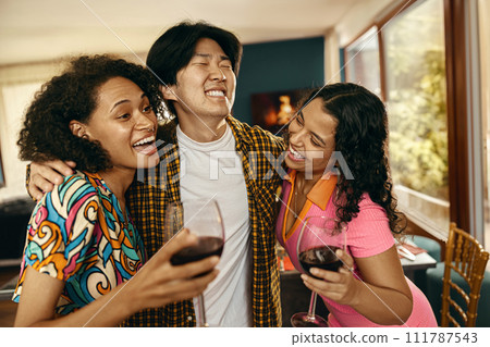 Happy young friends is drinking wine and hugging while having holiday dinner home party together 111787543