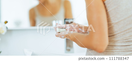 Closeup on young woman washing hands in bathroom with soap bar Closeup on young woman washing hands in bathroom with soap bar 111788347