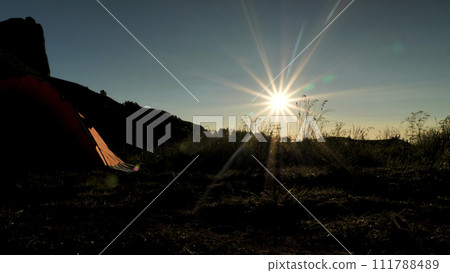 View of grass and tent lit by the bright morning sun. Beautiful lens flare. Tent camp in the mountains. View of grass and tent lit by the bright morning sun. Beautiful lens flare. Tent camp in the mountains. 111788489
