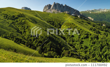 Picturesque colourful nature and high cliffs. Two rocks called Chertovy Vorota Devil's Gate . Lush green grass in the mountains and blue sky. 111788492