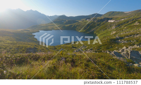 Beautiful blue lake in the mountains amongst rocks and grass. Dawn in the mountains. Hiking in the mountains in summer. Beautiful blue lake in the mountains amongst rocks and grass. Dawn in the mountains. Hiking in the mountains in summer. 111788537