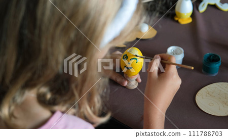 Rear view of little girl painting egg indoors, preparing for Easter holidays 111788703