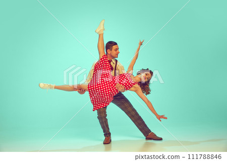 Swing dancers radiating happiness while performing energetic dance moves in motion against gradient mint background. 111788846
