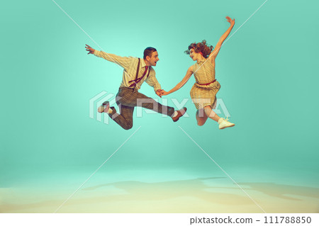 Portrait of modern jazz-dancers in mid-air against gradient mint background. Joyful dance partners performing dance. Vintage fashion. Portrait of modern jazz-dancers in mid-air against gradient mint background. Joyful dance partners performing dance. Vintage fashion. 111788850