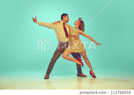 Beautiful woman and man looking at each other while dancing in motion against gradient mint background. 111788856