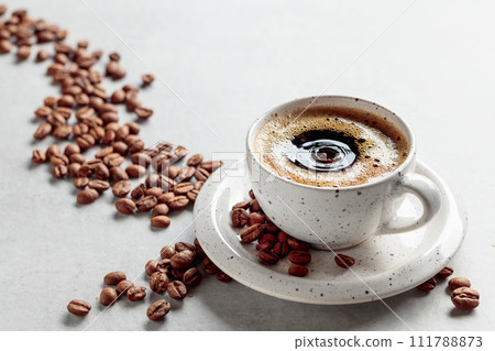 Black coffee and coffee beans on a white marble table. 111788873