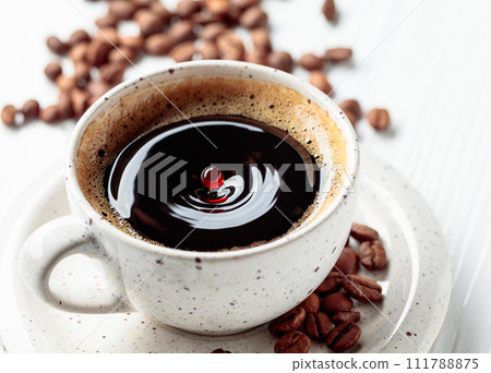 Black coffee and coffee beans on a white wooden table. Black coffee and coffee beans on a white wooden table. 111788875