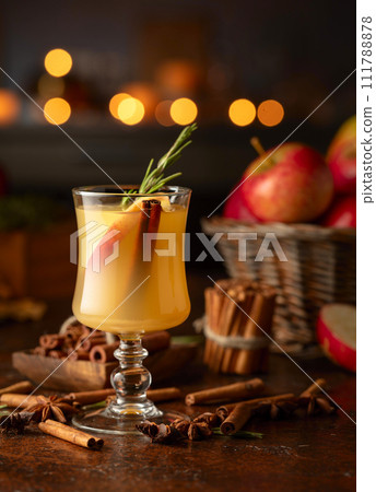 Mulled cider with apples, cinnamon, rosemary, and anise on a background of burning candles. 111788878