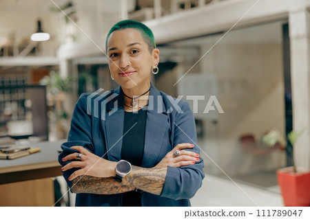 Portrait of smiling tattooed female freelancer with crossing hands on modern coworking background 111789047