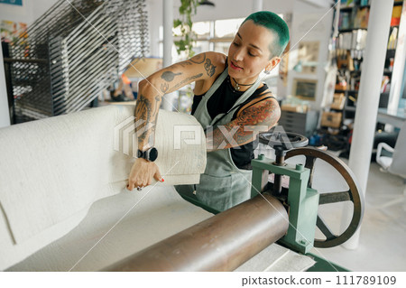 Female worker in apron use special equipment while working on design fabric Female worker in apron use special equipment while working on design fabric 111789109