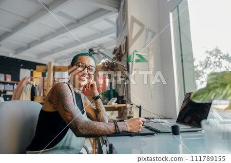 Female worker uses graphics tablet and laptop for retouching photos or digital drawing in studio Female worker uses graphics tablet and laptop for retouching photos or digital drawing in studio 111789155