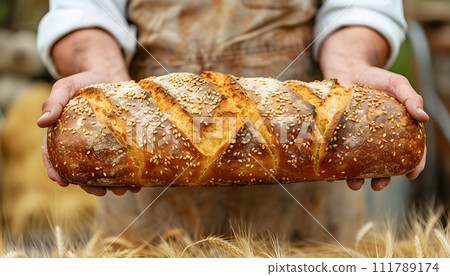 A man's hands hold a loaf of bread. 111789174